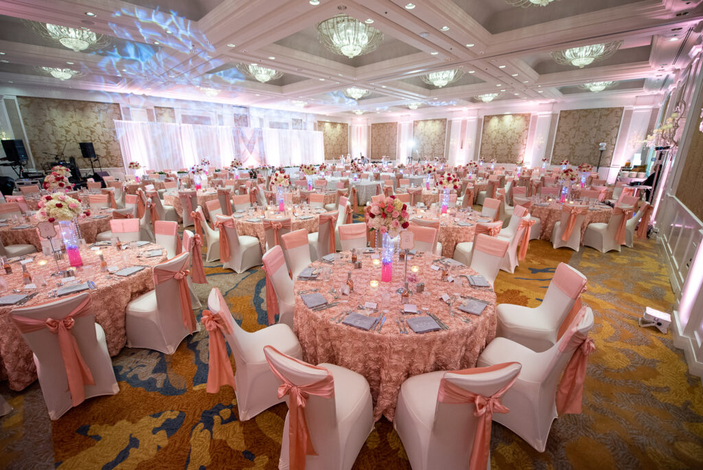 Hawaiian indoor wedding tables decorated with pink florals, tableware, and centerpieces.
