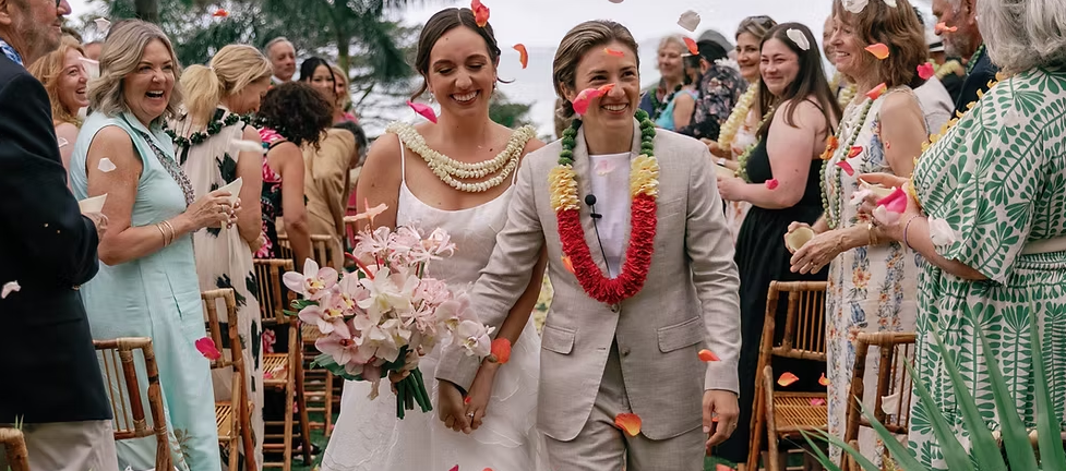Two brides walking down the aisle at their wedding, expertly planned by The Gay Agenda Collective in Hawaii.