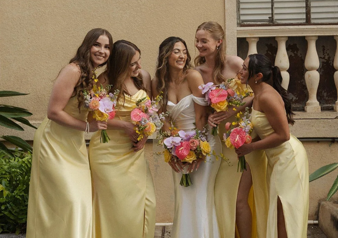 Bride and bridesmaids holding elegant bouquets designed by Designs by Hemingway Florist in Hawaii during a wedding celebration.