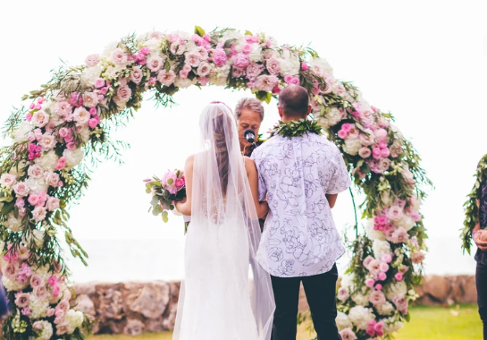 Wedding ceremony flower arch by Marie Blooms Floral featuring romantic blooms framing the couple during their vows.