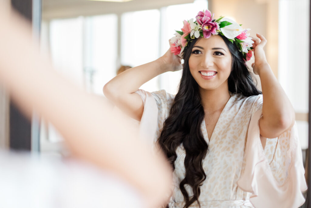 Bride placing her hairpiece lei in her hair prior to her Hawaiian wedding.