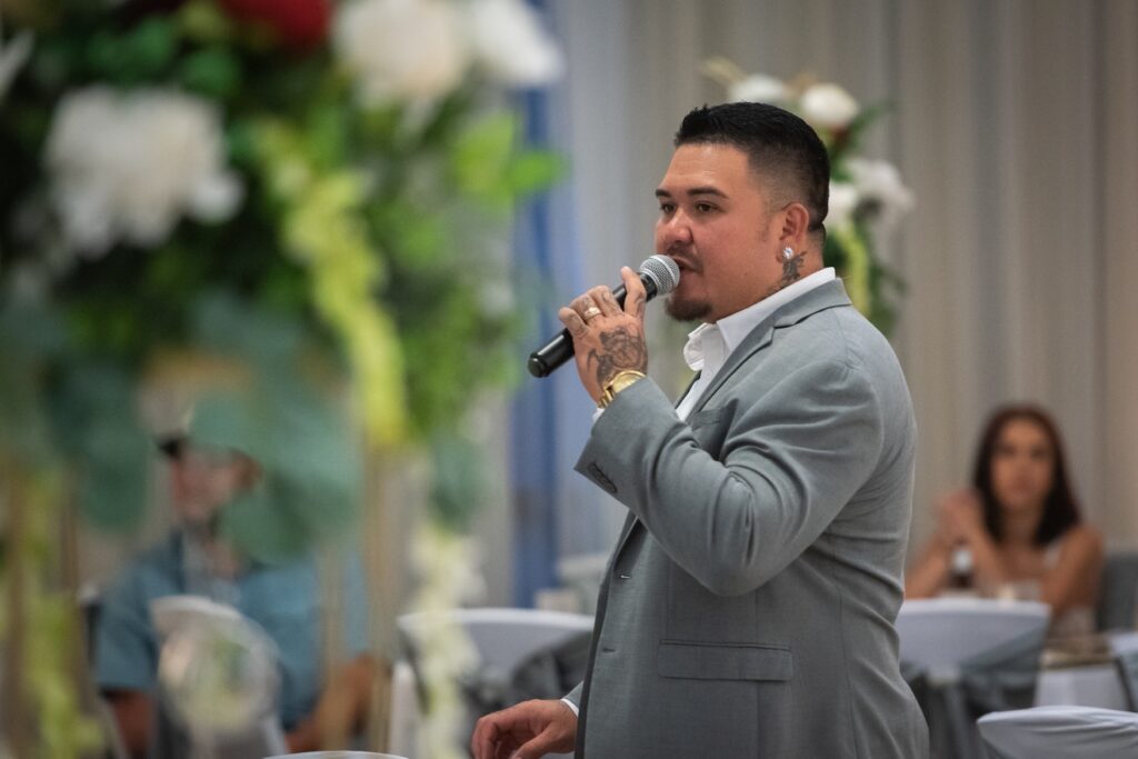 Wedding emcee speaking into a microphone at a reception, illustrating how much to tip wedding vendors.
